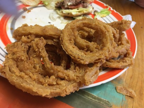 A plate of crispy, golden-brown onion rings stacked together.