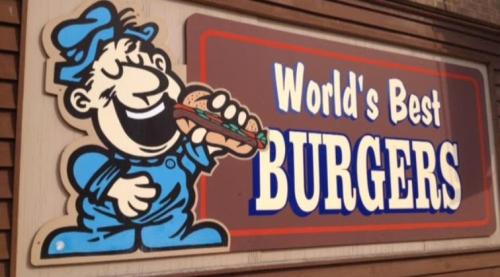 A cartoon character in blue overalls happily holds a sandwich, with the text "World's Best Burgers" on a sign.