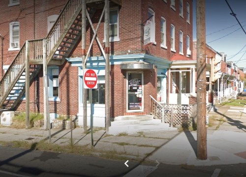 A brick building with a staircase, a "Do Not Enter" sign, and nearby power lines on a sunny day.