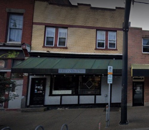 A storefront with a green awning, featuring large windows and a sign that reads "Culinary Avenue."