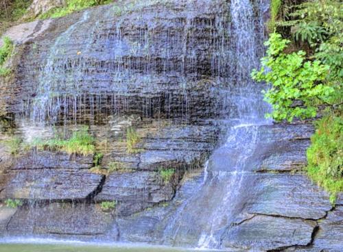A serene waterfall cascading over rocky cliffs, surrounded by lush greenery.