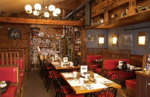 Cozy restaurant interior with wooden decor, red booths, and tables set for dining, featuring a wall of vintage items.