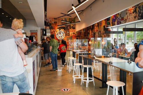 A vibrant restaurant interior with colorful artwork, patrons at tables, and a family with a child.