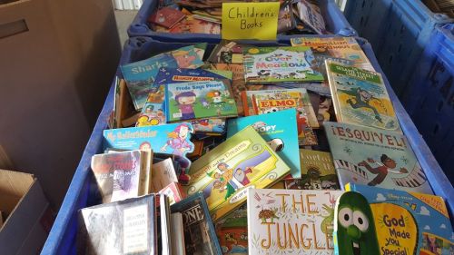 A large bin filled with various children's books, including colorful covers and titles like "The Jungle" and "Elmo."