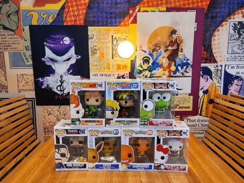 A collection of Funko Pop figures displayed on a table, featuring characters from various anime and video games.