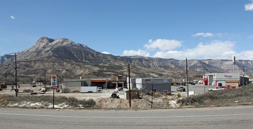 A view of a small commercial area with mountains in the background under a clear blue sky.