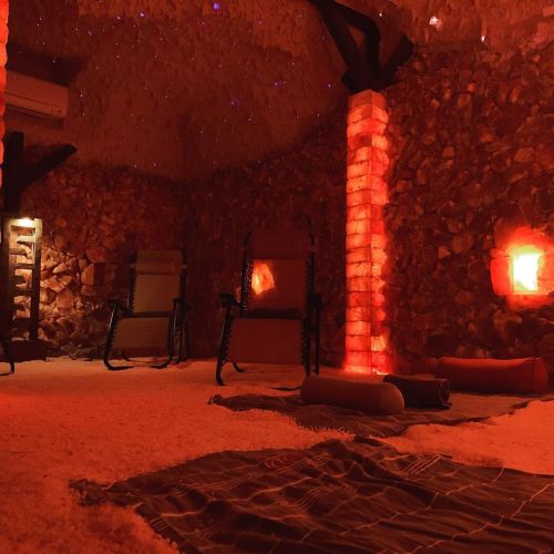 A cozy salt room with glowing salt brick walls, reclining chairs, and soft lighting, creating a relaxing atmosphere.
