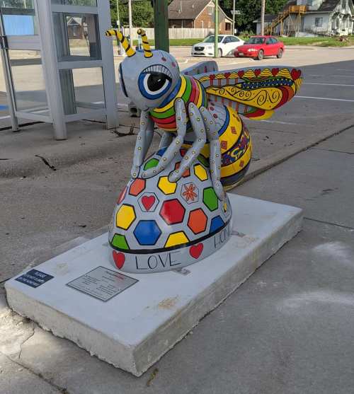 Colorful bee sculpture on a hexagonal base with hearts and the word "LOVE" displayed.