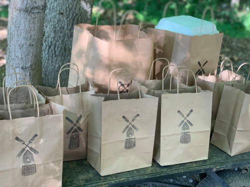 A collection of brown paper bags with a windmill design, arranged on a table in a wooded area.
