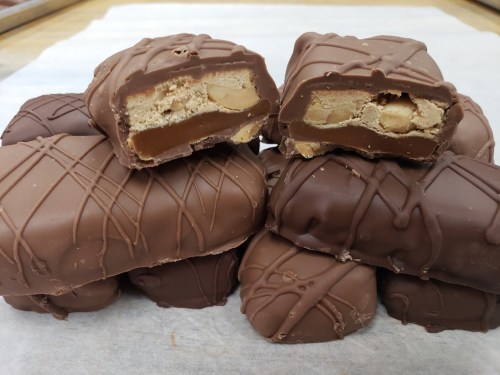A stack of chocolate bars, some cut in half to reveal a creamy filling with nuts inside.
