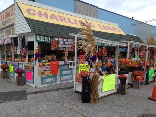 A colorful seafood market with pumpkins, flowers, and festive decorations, showcasing fresh produce and seafood.