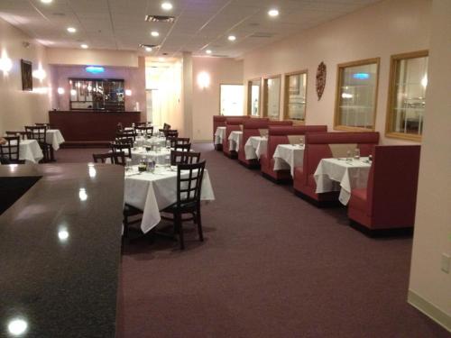 Interior of a restaurant featuring tables with white tablecloths and red booths, with a bar area in the background.