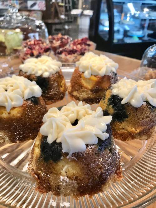 A close-up of small bundt cakes topped with cream frosting, displayed on a glass platter.