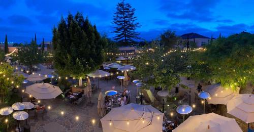 A beautifully lit outdoor restaurant patio at dusk, with umbrellas, string lights, and lush greenery.