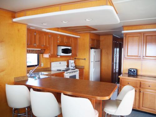 Modern kitchen with wooden cabinetry, white appliances, a breakfast bar, and ample counter space. Bright and inviting atmosphere.