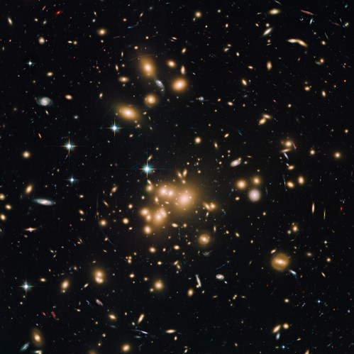A vast galaxy cluster filled with numerous bright galaxies and stars against a dark cosmic background.
