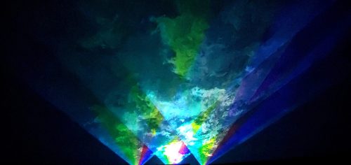 Colorful light beams and abstract patterns create a vibrant, dynamic display against a dark background.