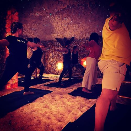 A group of people practicing yoga in a serene, salt cave environment with soft lighting and a peaceful atmosphere.