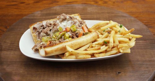 A plate with a sandwich filled with shredded meat and toppings, accompanied by a side of golden French fries.