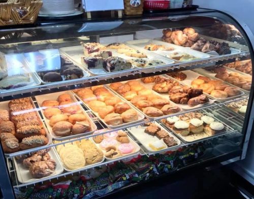 A display case filled with a variety of baked goods, including pastries, donuts, and cookies.