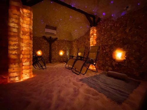 A tranquil salt room with glowing salt walls, lounge chairs, and soft lighting, creating a serene atmosphere.
