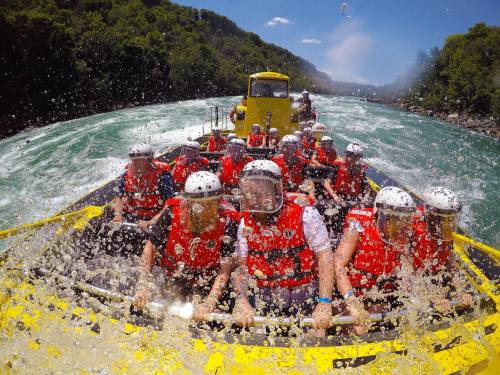 A group of people in red life jackets and helmets enjoying a thrilling white-water rafting experience on a river.