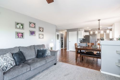 Cozy living area with a gray sofa, dining table, and modern kitchen in a bright, open-concept space.
