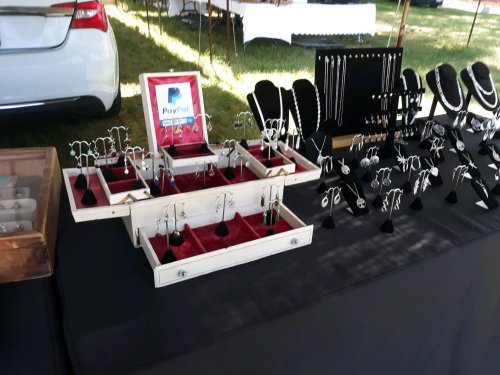 A display of jewelry including earrings and necklaces on a table, with a PayPal sign in a red frame.