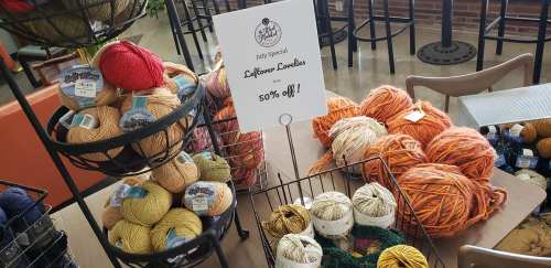 A display of colorful yarns with a sign promoting 50% off leftover bundles for a July special.