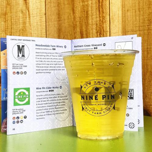 A clear cup of cider sits in front of a map featuring local beverage trails and wineries.