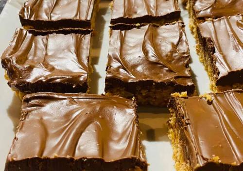 Close-up of chocolate-covered bars, cut into squares, arranged neatly on a white plate.
