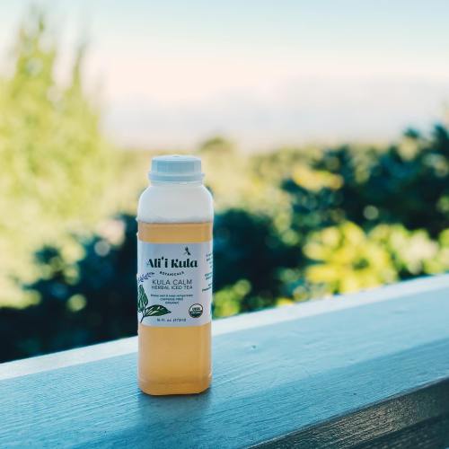 A bottle of herbal iced tea sits on a ledge with a blurred natural background.