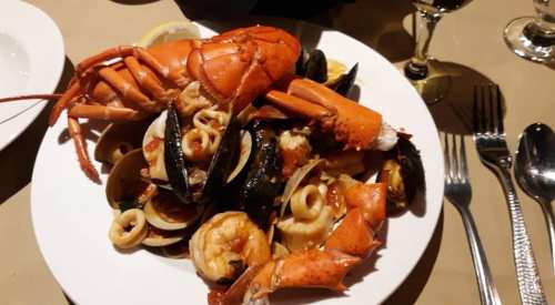A plate of seafood featuring lobster, shrimp, clams, and mussels, garnished with lemon slices.