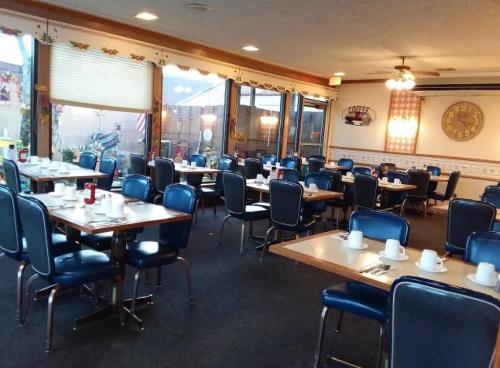 A cozy diner with blue chairs and tables set for breakfast, featuring coffee cups and a clock on the wall.