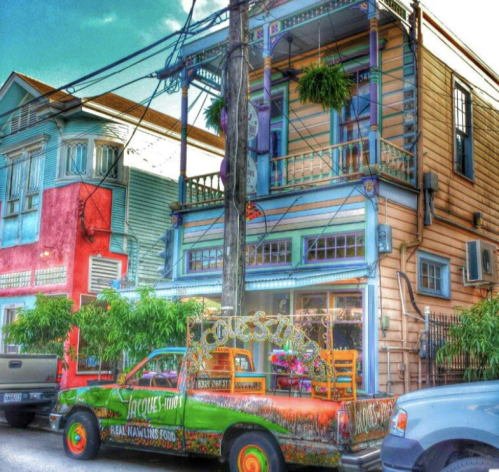 A colorful truck parked in front of a vibrant building with plants, showcasing a lively street scene.