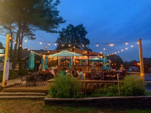 A cozy outdoor restaurant with string lights, teal umbrellas, and diners enjoying the evening ambiance.