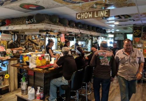 A lively bar scene with patrons at the counter, decorated with memorabilia and a sign reading "Chow Line."