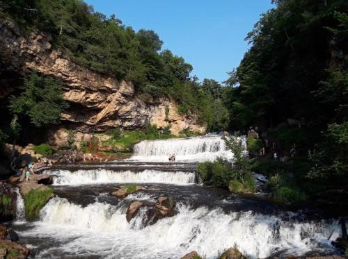 A scenic waterfall surrounded by lush greenery, with people enjoying the natural beauty nearby.