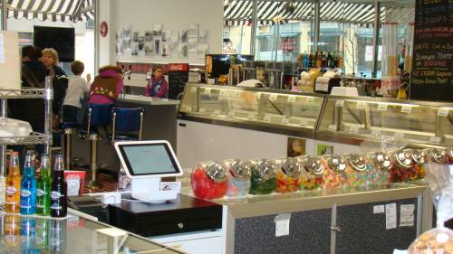 A colorful ice cream shop interior with candy jars, a display case, and customers enjoying treats.