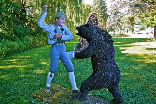 A statue of a man in traditional attire confronting a bear in a green park setting.