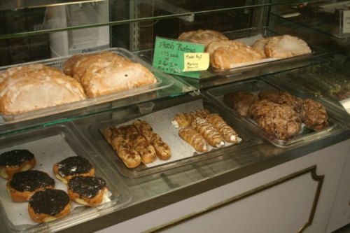 A display case filled with various pastries, including glazed turnovers, cream-filled pastries, and chocolate-covered treats.