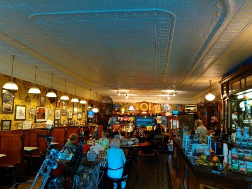 A cozy diner with vintage decor, featuring patrons at tables and a long counter filled with memorabilia.