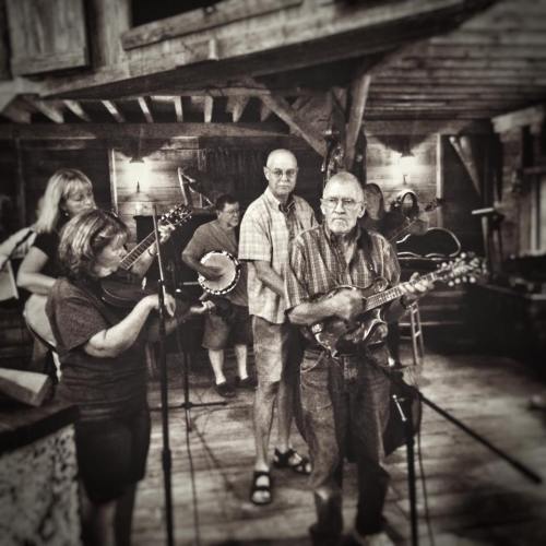 A group of musicians playing instruments in a rustic setting, creating a lively atmosphere.
