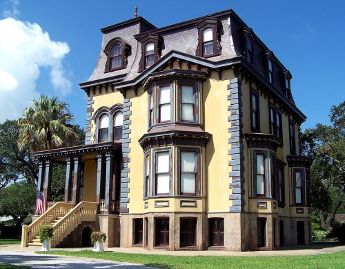 A large, historic Victorian-style house with a unique design, featuring multiple gables and a wraparound porch.