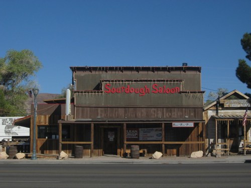 A rustic wooden building with a sign reading "Sourdough Saloon" against a clear blue sky.
