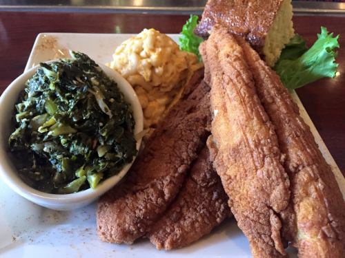 A plate featuring fried catfish, collard greens, macaroni and cheese, and cornbread.