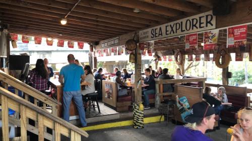 A lively restaurant interior with patrons dining, wooden beams, and colorful banners hanging from the ceiling.