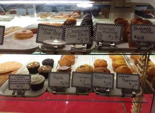 Display case filled with various baked goods, including muffins and cupcakes, with price tags visible.