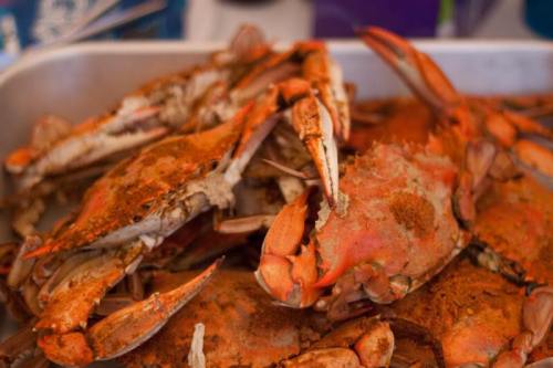 A close-up of a tray filled with seasoned, cooked crabs, showcasing their vibrant orange shells.