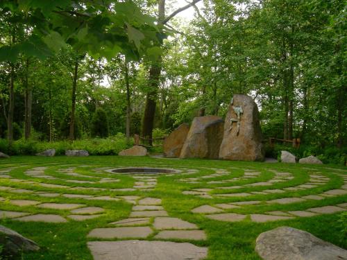 A stone labyrinth surrounded by lush greenery, featuring large rocks and a central circular area.